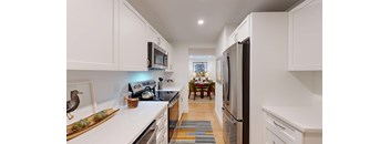 A kitchen with white cabinets and a black refrigerator.