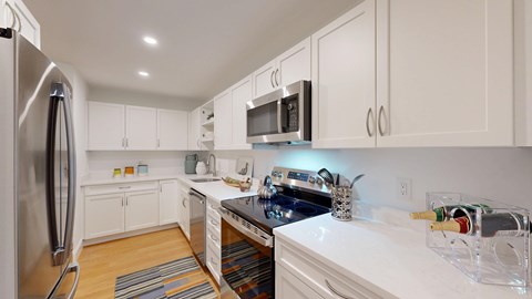 A kitchen with white cabinets and a stainless steel refrigerator.