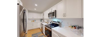 A kitchen with white cabinets and a stainless steel refrigerator.