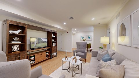 A living room with a grey couch, a wooden entertainment center, and a white coffee table.