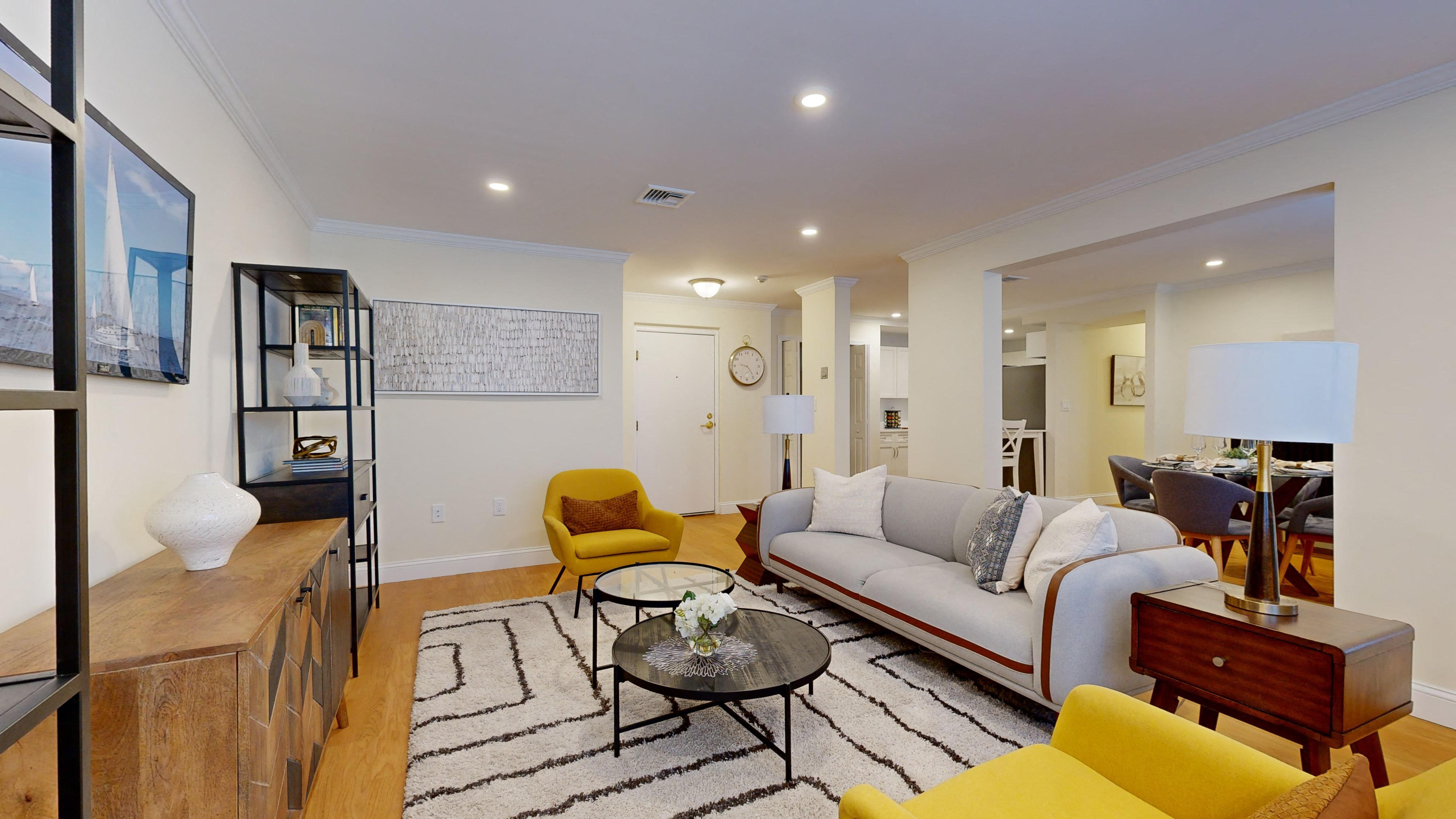 A living room with a yellow chair and a white couch.