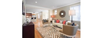 A living room with a white couch and a brown and white striped rug.