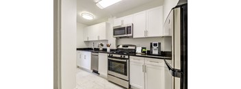 A kitchen with white cabinets and black countertops.