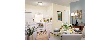 A modern kitchen with a glass dining table set for two.