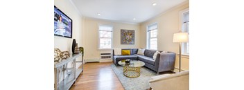A living room with a grey couch and a television on the wall.