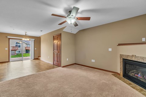 A living room with a fireplace and a ceiling fan.