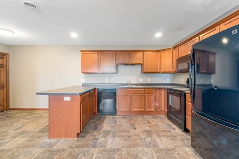 A kitchen with wooden cabinets and a black refrigerator.
