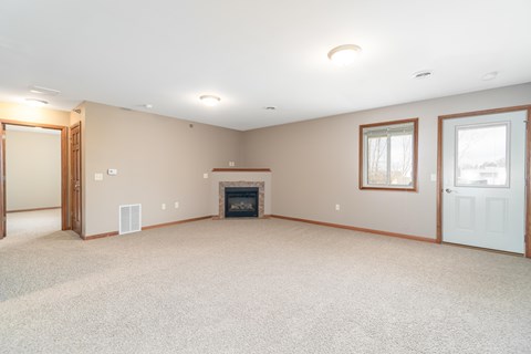 A spacious living room with a fireplace and carpeted floor.
