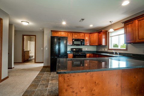 A kitchen with wooden cabinets and a black refrigerator.