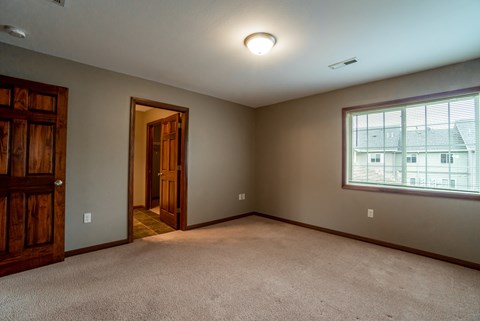 A room with a carpeted floor and a window showing a building outside.