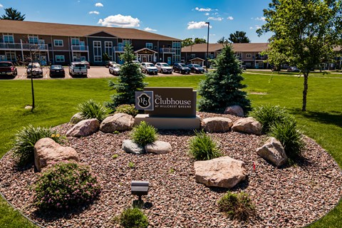 A landscaped area with a sign that says "Clubhouse" in front of a building.