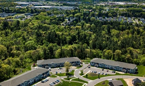 A large building complex surrounded by trees and a parking lot.