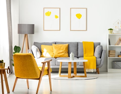 A living room with a grey couch, yellow chair, and two yellow pillows.