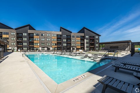 A large swimming pool in front of a multi-story apartment building.
