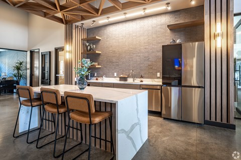 A modern kitchen with a bar area and chairs.