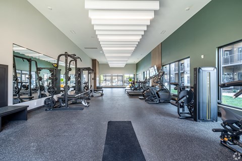 A spacious gym with a variety of equipment and a long mirrored wall.