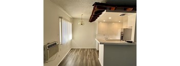 A kitchen with a white countertop and wooden flooring.
