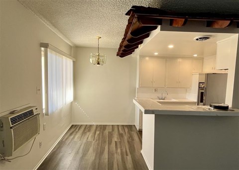 A kitchen with a white countertop and wooden flooring.