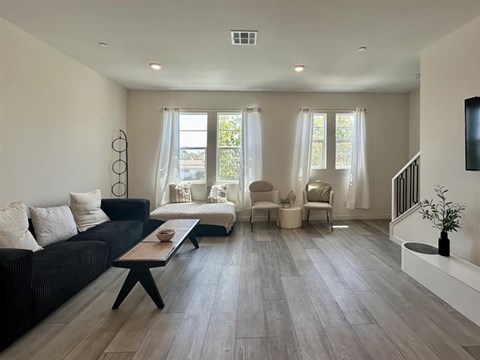 A living room with a black couch and a wooden coffee table.