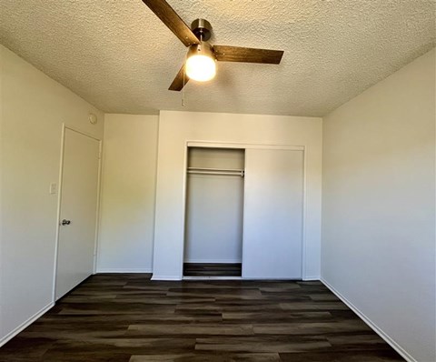 A room with a ceiling fan and wooden flooring.