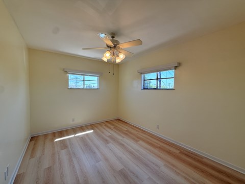 A room with wooden flooring and a ceiling fan.