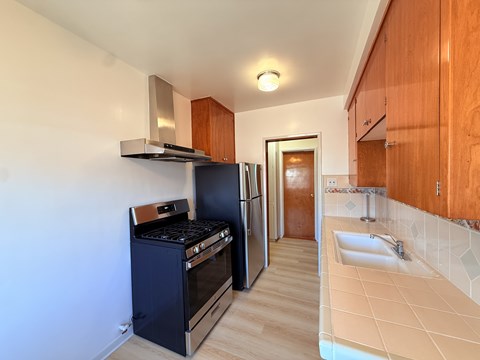 A kitchen with a black oven and wooden cabinets.