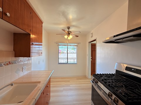 A kitchen with a stove, sink, and a window.