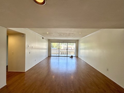 A large empty room with wooden floors and white walls.