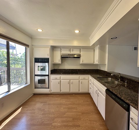A kitchen with white cabinets and a black countertop.