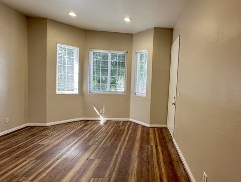 A room with wooden floors and two windows.