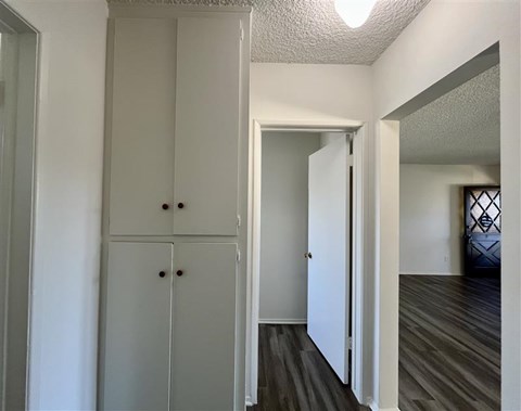 A white cabinet with two doors and two drawers is in a room with wood flooring.
