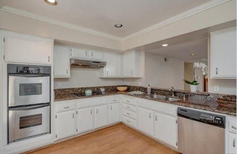 A kitchen with white cabinets and a granite countertop.