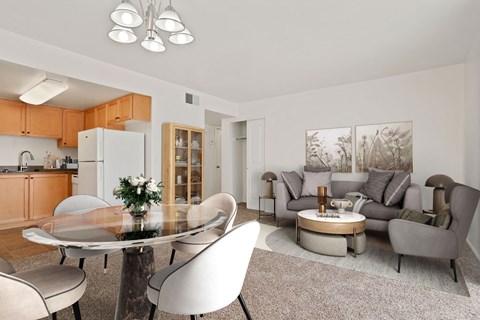 A modern dining room with a glass table and white chairs.