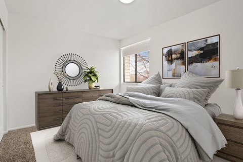 A bedroom with a large bed and a round mirror on the wall.