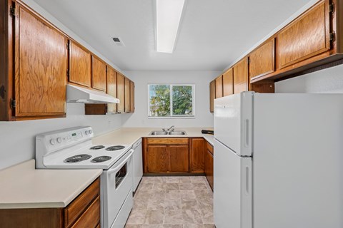 A kitchen with white appliances and wooden cabinets.