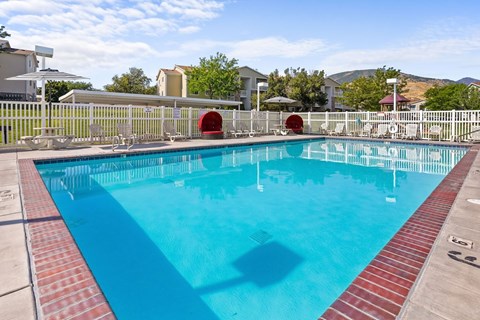 A large outdoor swimming pool with a red brick border.