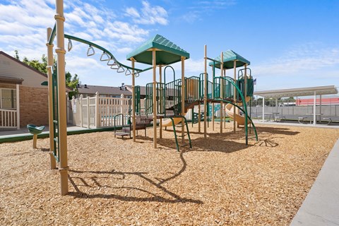 A playground with a green slide and wooden structure.