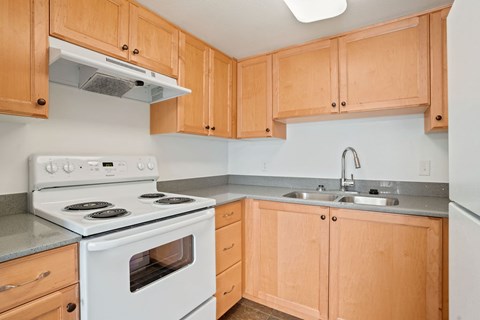 A kitchen with a white stove and wooden cabinets.