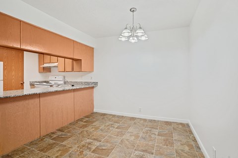 A kitchen with brown cabinets and a tiled floor.