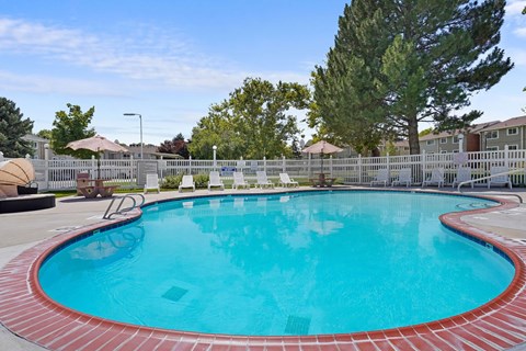 A large outdoor swimming pool surrounded by a white fence.