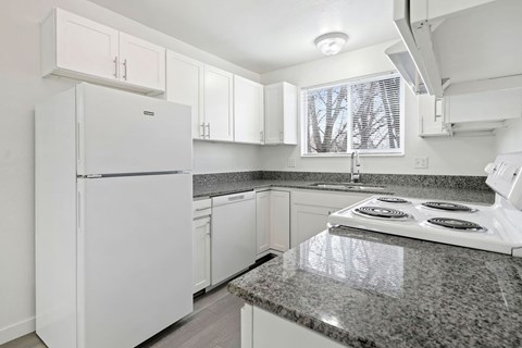 A kitchen with a white fridge and stove top.