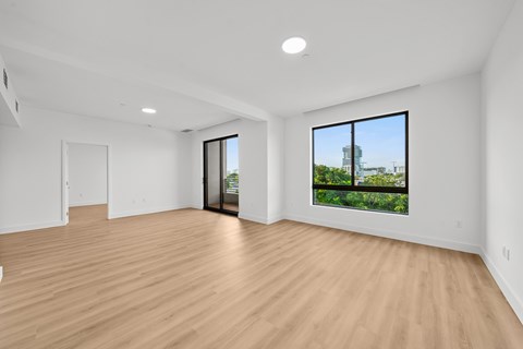 A room with wooden floors and a view of a building outside the window.