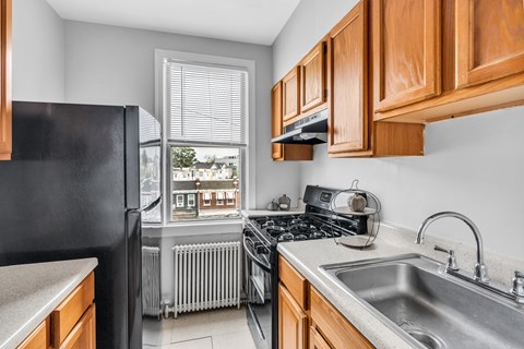 A kitchen with a black refrigerator and wooden cabinets.