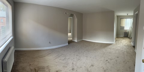 A spacious room with beige carpeting and white walls.