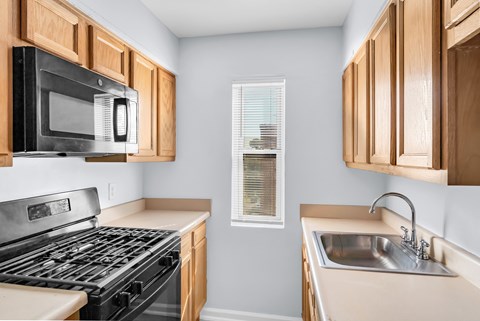 A kitchen with a black stove top oven and a black microwave above it.