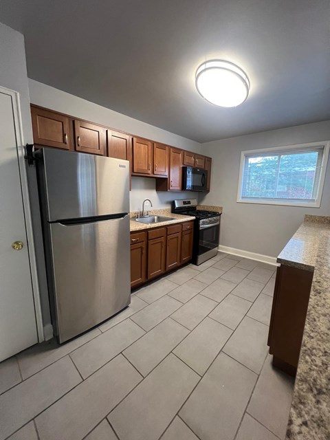 A kitchen with a refrigerator, microwave, and oven.