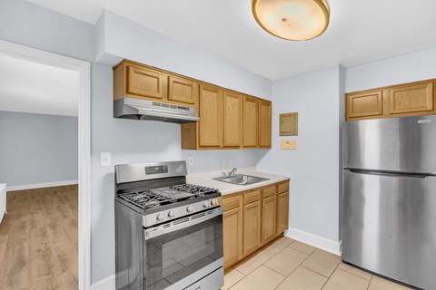 A kitchen with a stove, sink, and refrigerator.