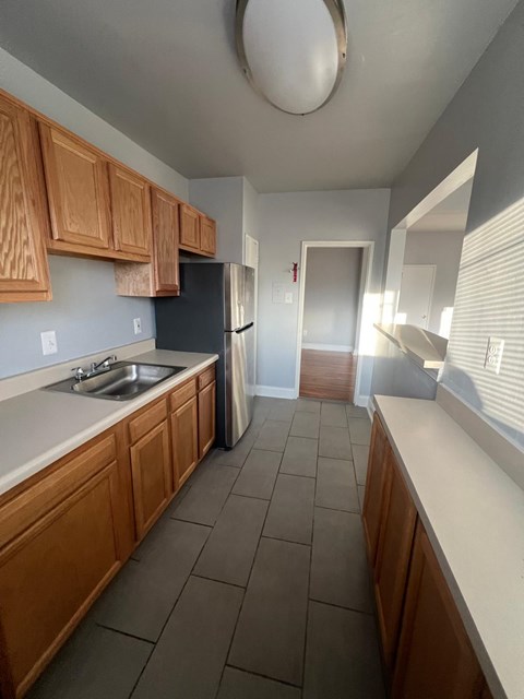 A kitchen with wooden cabinets and a black refrigerator.