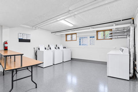 A laundry room with a washer and dryer on the wall and a table in the middle.