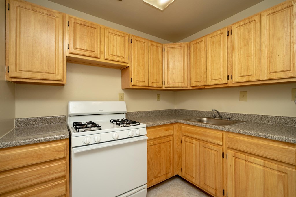 a kitchen with wooden cabinets and a stove and a sink
